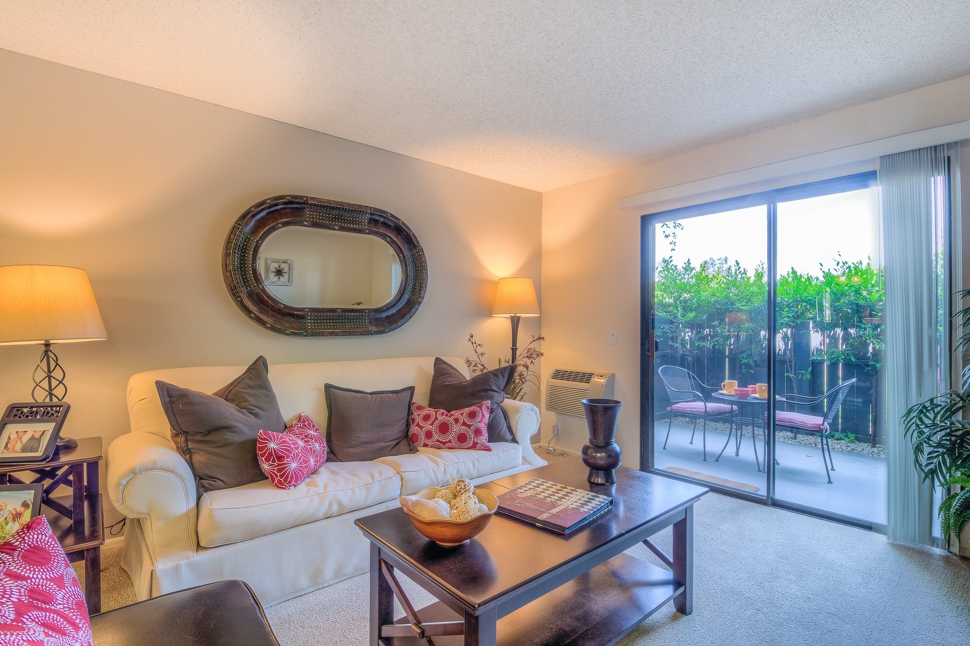 A living room with a white couch, a coffee table, and a large mirror on the wall.,A living room with a white couch, a coffee table, and a large mirror on the wall.